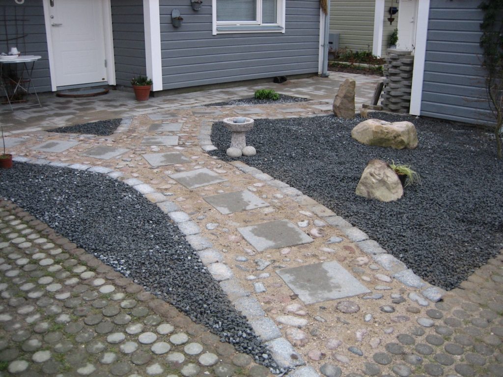 Indgangssti til hus i elegant stil med trædesten, brosten og herregårdssten